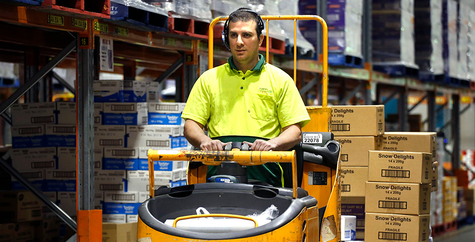 woolworth's employee driving forklift in distribution warehouse